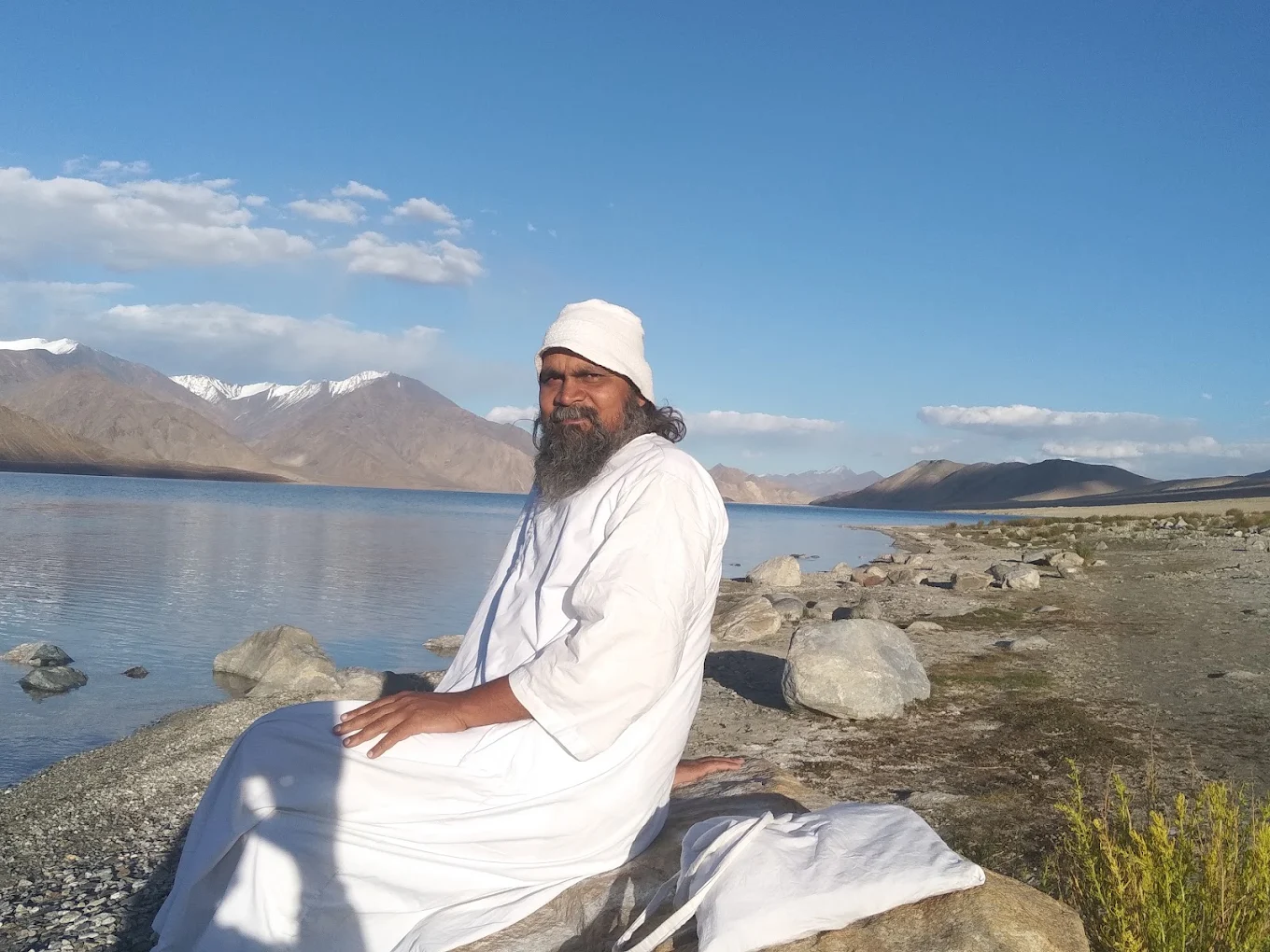 Swami Ashok Samdarshi seated beside a high-altitude lake in the Himalaya