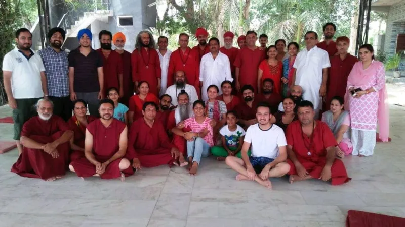 A large workshop group on a marble terrace, many in maroon robes