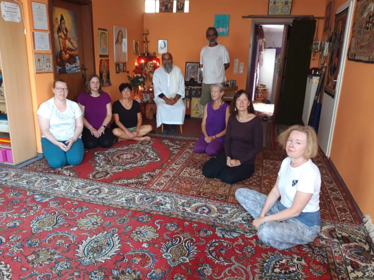 A group seated on a patterned carpet in a room with an altar
