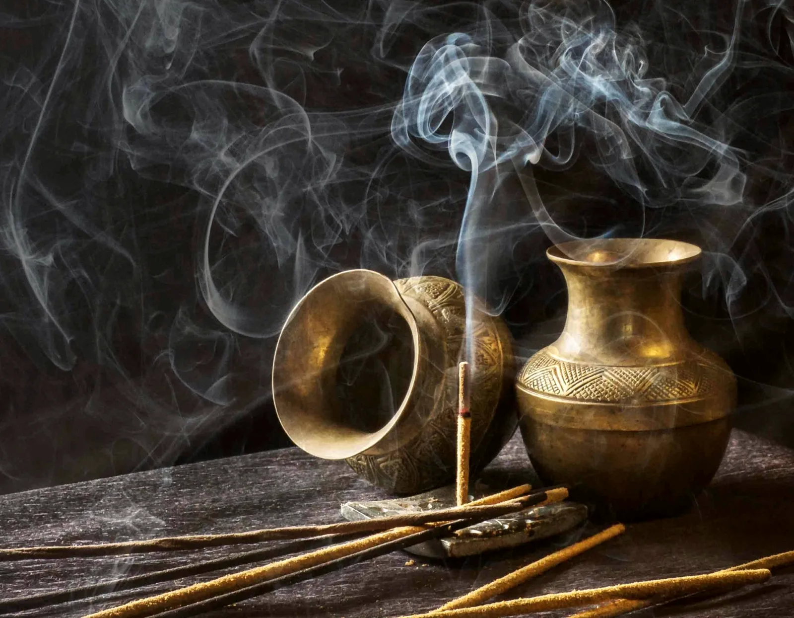 Incense burning beside brass vessels, the smoke curling in still air