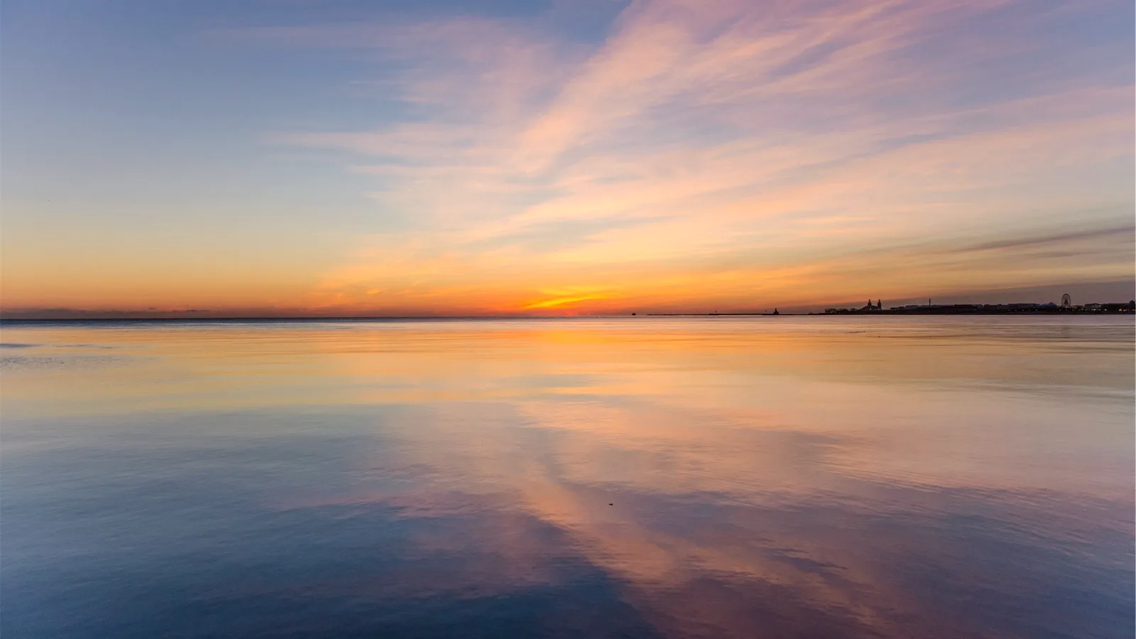 A calm stretch of water mirroring a wide sunset sky