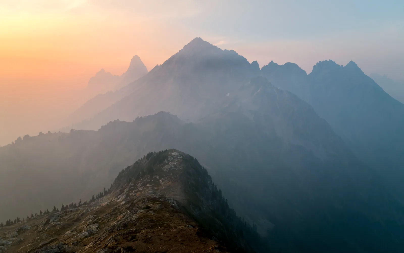 Layered mountain ridges fading into mist at first light